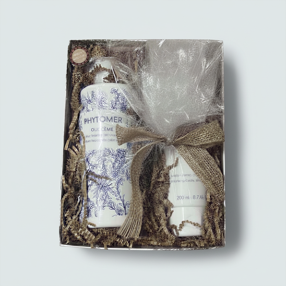 Gift set with Phytomer skincare products wrapped in brown paper with a bow on a light gray background
